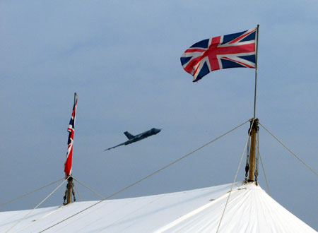 A Vulcan bomber flies over the flag-bedecked 'Spitfire Café' refreshment tent at Goodwood Revival