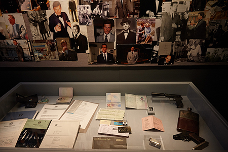 Showcase of personal effects sits in front of a collage of James Bond images